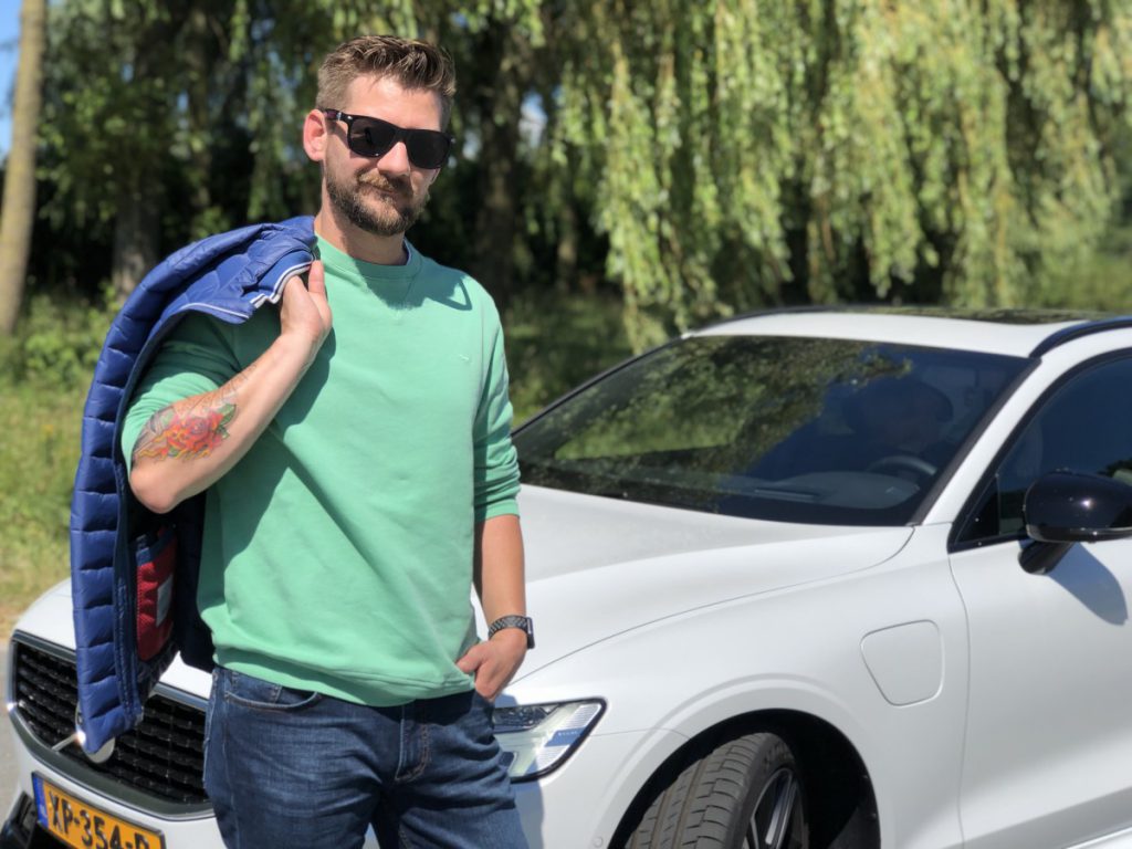 Jan Willem Huffmeijer staat voor de Volvo V60 en draagt de outfit van  Brax mannenmode