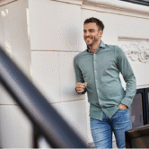 Man met mooie outfit leunt tegen muur