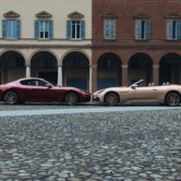 Twee exclusieve Maserati’s – de GranTurismo en GranCabrio Meccanica Lirica – staan neus aan neus op het plein in Modena, voor de historische Italiaanse arcades.