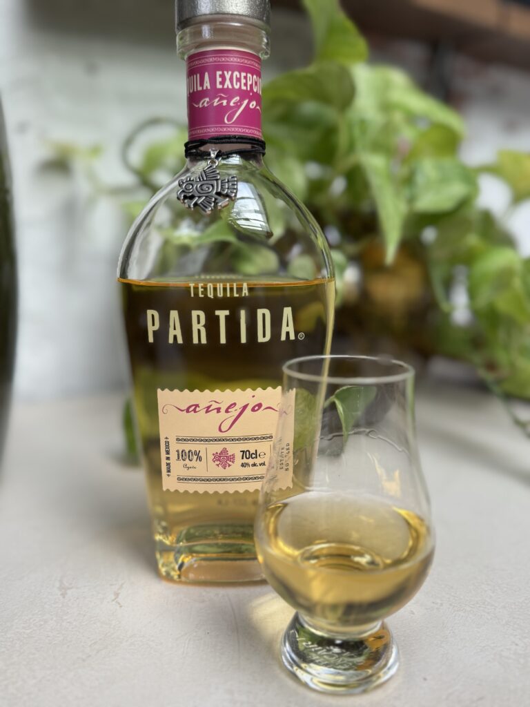 Fles van de partida añejo met een glas ernaast ingeschonken klaar om te proeven